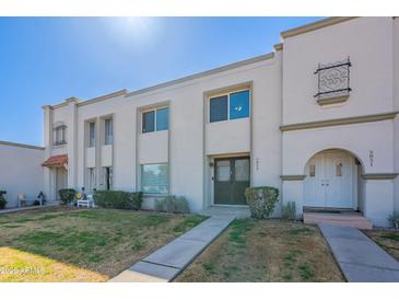 Inviting townhome exterior showcasing desert landscaping and white facade under a sunny sky at 5853 E Thomas Rd, Scottsdale, AZ 85251