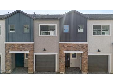 Exterior view of townhomes with brick accents, garage doors, and varying gray siding at 2825 W Eagle Talon Rd, Phoenix, AZ 85085