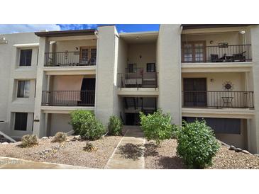 Attractive condo building featuring balconies, neutral stucco, and desert landscaping at 5518 E Lindstrom Ln # 1034, Mesa, AZ 85215