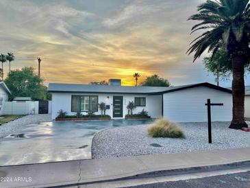 Charming single-story home with modern updates and a well-maintained front yard, set against a beautiful sunset backdrop at 6326 N 86Th N St, Scottsdale, AZ 85250