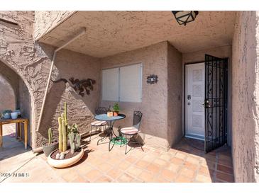 Inviting front porch with red tile, stylish metal lizards, and a cozy table and chairs for outdoor enjoyment at 7312 N Via Camello Del Norte St # 95, Scottsdale, AZ 85258