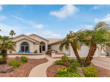 Charming home featuring desert landscaping with palm trees and a welcoming walkway leading to the front door at 15816 W Amelia Dr, Goodyear, AZ 85395