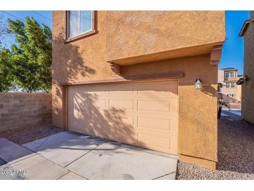 Exterior view of attached one car garage in neutral color with large cement driveway and a brick wall at 1940 N 78Th Gln, Phoenix, AZ 85035