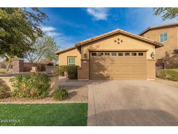 Charming home featuring manicured landscaping, a brick driveway, and an attached two-car garage at 412 W Lyle Ave, San Tan Valley, AZ 85140