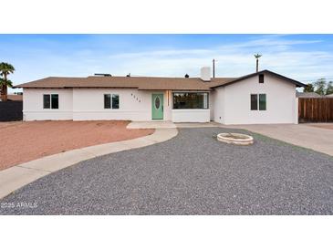 Charming single-story home features desert landscaping, a light-colored exterior, and a bright green front door at 8220 N 35Th Ave, Phoenix, AZ 85051