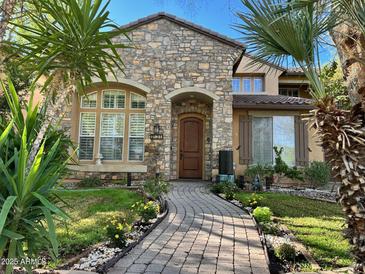 Charming stone-clad home with a winding brick path and lush tropical landscaping at 1131 W Sierra Madre Ave, Gilbert, AZ 85233