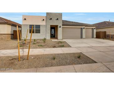 Contemporary home featuring a three car garage and desert landscaping at 14770 W Tether Trl, Surprise, AZ 85387