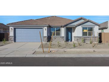 Charming single-story home with stone accents, well-manicured landscaping, and a two-car garage at 14790 W Tether Trl, Surprise, AZ 85387