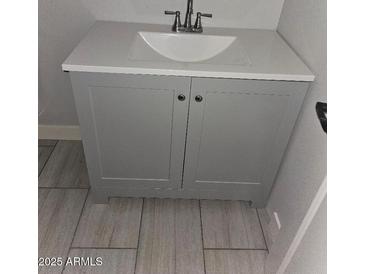 Bathroom vanity with white top, gray cabinets, and updated fixtures at 4002 N 58Th Dr, Phoenix, AZ 85031