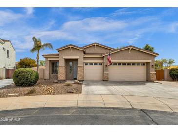 Beautiful single-story home with stone accents, three-car garage, desert landscaping, and an American flag displayed at 6271 S Twilight Ct, Gilbert, AZ 85298