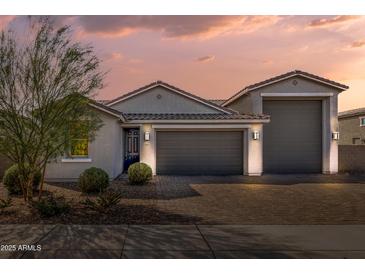 Charming single-story home with a three-car garage and a desert-landscaped front yard at dusk at 1627 E Walter Dr, Casa Grande, AZ 85122