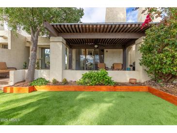 Inviting covered back patio with lush landscaping and comfortable outdoor seating overlooking a well-manicured artificial lawn at 2537 N Miller Rd, Scottsdale, AZ 85257