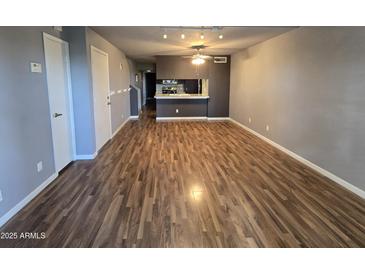 Open-concept living room featuring wood floors and modern lighting fixtures flowing into an open kitchen at 30 E Brown Rd # 2052, Mesa, AZ 85201