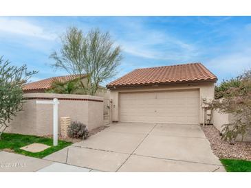 Beige two car garage and private driveway with a red-tiled roof surrounded by desert landscaping at 10957 E Hope Dr, Scottsdale, AZ 85259