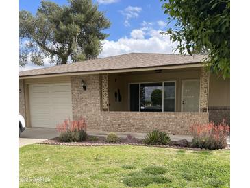 Charming home featuring a well-maintained lawn, desert landscaping, and a brick facade at 11001 W Tonada Dr, Sun City, AZ 85351