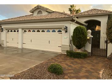 Charming home featuring a three car garage, tile roof, and decorative wrought iron gate and walkway at 16167 W Monterey Way, Goodyear, AZ 85395