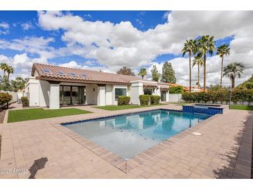 Backyard pool with brick patio and desert landscaping surrounding a white, modern home at 9675 E Cinnabar Ave, Scottsdale, AZ 85258