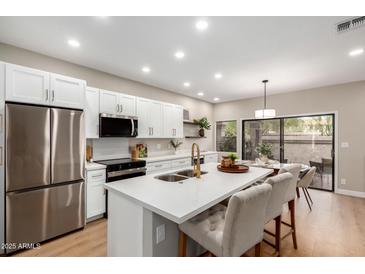 Bright kitchen featuring stainless steel appliances, white cabinets, and a center island with bar seating at 9705 E Mountain View Rd # 1056, Scottsdale, AZ 85258