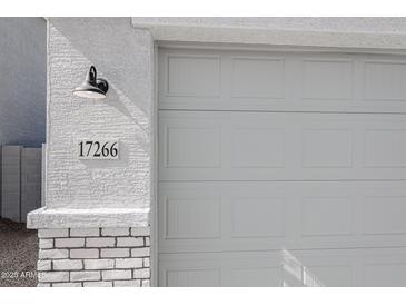 Close-up of the garage door with a house number and exterior light fixture at 17266 W Daley Ln, Surprise, AZ 85387