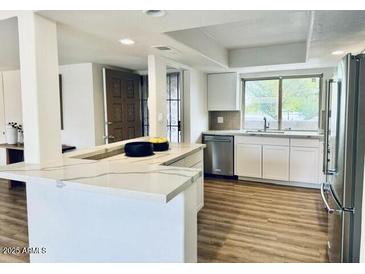 Bright kitchen features white cabinets, stainless steel appliances, and a large island with quartz countertops at 7232 N Via Camello Del Norte -- # 3, Scottsdale, AZ 85258