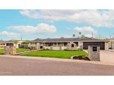 Charming single-story home featuring a well-manicured lawn, stone accents, and a private driveway at 7417 E Bonita Dr, Scottsdale, AZ 85250