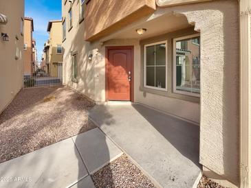 Inviting front entrance with a vibrant orange door and well-maintained landscaping at 7720 W Pipestone Pl, Phoenix, AZ 85035