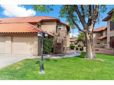 Charming condo featuring a lush green lawn and classic Southwest architecture with a red tile roof at 8700 E Mountain View Rd # 2058, Scottsdale, AZ 85258