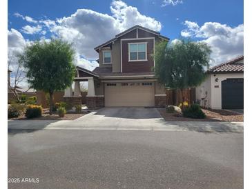 Charming two-story home featuring a two-car garage, manicured trees, and beautiful blue skies at 9207 W Sells Dr, Phoenix, AZ 85037