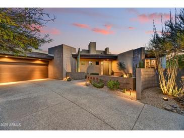 Contemporary home showcasing desert landscaping, a covered garage, and unique architectural design at sunset at 10567 E Fernwood Ln, Scottsdale, AZ 85262