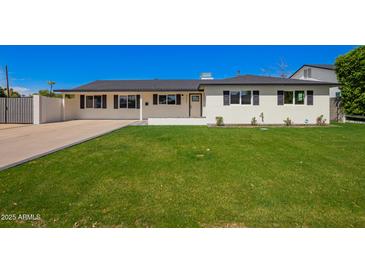 Inviting single-story home featuring a lush green lawn and a classic white exterior with black shutters at 4402 E Mitchell Dr, Phoenix, AZ 85018