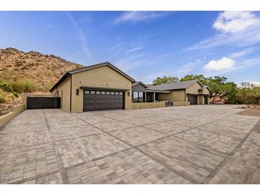 Long shot of an elegant home featuring multiple garages, desert landscaping, and a private gated entrance at 5301 E Paradise Canyon Rd, Paradise Valley, AZ 85253