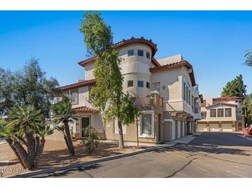 Stucco two-story home featuring a red tile roof, a charming turret, and mature landscaping at 7420 E Northland Dr # B101, Scottsdale, AZ 85251