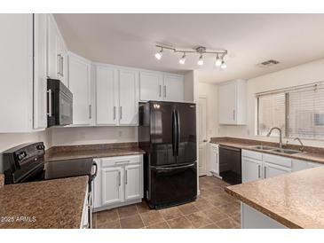 An open kitchen with white cabinets, stainless steel appliances, and a tile floor at 18856 N Comet Trl, Maricopa, AZ 85138