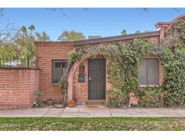 Quaint brick home featuring a vine-covered arched entryway and a landscaped yard at 3002 N 32Nd St # 13, Phoenix, AZ 85018