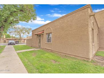 Tan home featuring a lush lawn, secure door, and shaded by a large tree at 4258 N 68Th Dr, Phoenix, AZ 85033