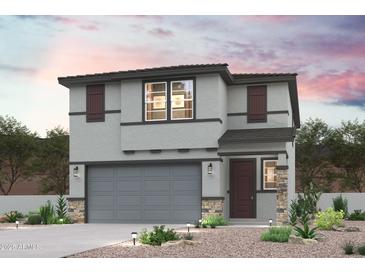 Charming two-story home featuring a gray stucco exterior, stone accents, and well-maintained landscaping at 17229 W Daley Ln, Surprise, AZ 85387