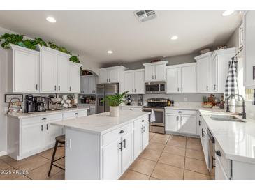 Bright kitchen with white cabinets, stainless steel appliances, an island, and stone countertops at 24805 W Vista Norte St, Buckeye, AZ 85326