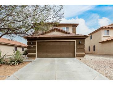 Tan two-story home featuring a two-car garage with a brown door and desert landscaping at 31527 N Sundown N Dr, San Tan Valley, AZ 85143