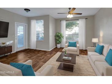 Bright living room featuring wood floors, a ceiling fan, and comfortable seating arrangements at 5303 N 7Th St # 134, Phoenix, AZ 85014