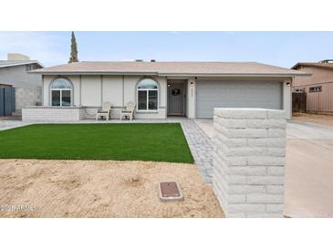 Charming single-story home features a manicured lawn, covered porch with chairs, and an attached two-car garage at 6225 W Mary Jane Ln, Glendale, AZ 85306