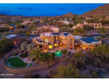 Stunning aerial view of luxury home, pool, putting green and desert landscaping at twilight at 10707 E Cottontail Ln, Scottsdale, AZ 85255