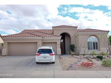 Charming single-story home with a three-car garage, desert landscaping, and a tile roof at 13487 E Gold Dust Ave, Scottsdale, AZ 85259