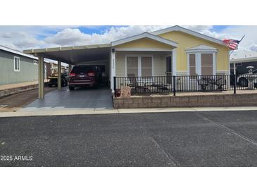 Charming home featuring covered parking, a cozy front patio with chairs, and an American flag at 650 N Hawes Rd # 4326, Mesa, AZ 85207