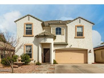 Charming two-story home features a welcoming front porch, two-car garage, and landscaped front yard at 1622 E Silverbirch Ave, Buckeye, AZ 85326