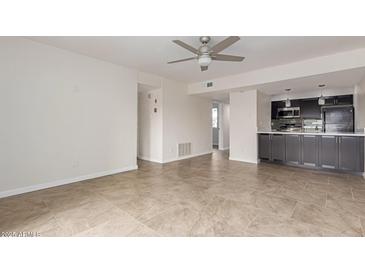 Bright living room with ceiling fan and adjacent kitchen featuring dark cabinetry and tile flooring at 3314 N 68Th St # 247, Scottsdale, AZ 85251
