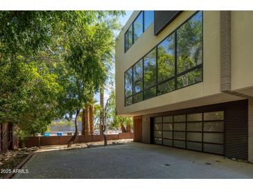 Modern home exterior featuring a large garage door and contemporary architectural design surrounded by lush trees at 4507 N 12Th St # 6, Phoenix, AZ 85014