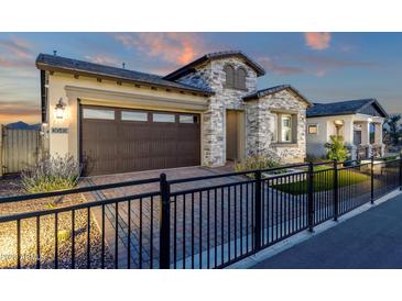 Charming single-Gathering home featuring stone accents, a dark brown garage, and brick paved driveway at 5748 E Sierra Morena St, Mesa, AZ 85215