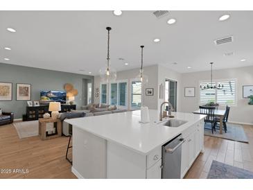 Bright, open kitchen with island seating, white cabinets, and an adjoining living space at 9734 E Spiral Ave, Mesa, AZ 85212