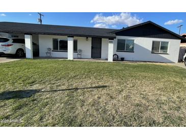 Charming single-story home featuring a well-maintained lawn and a welcoming front porch with seating at 1132 E 9Th Pl, Casa Grande, AZ 85122