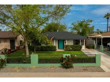 Charming home with a well-maintained front yard, a blue front door, and a stylish fence at 1326 E Almeria Rd, Phoenix, AZ 85006